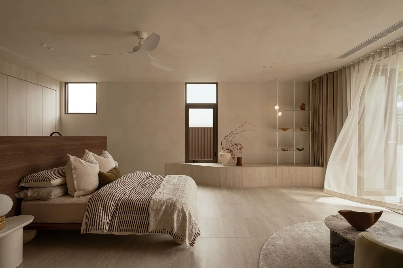 A bedroom at ZOEI with soft natural light and travertine walls, suited to fashion and linen photoshoots.