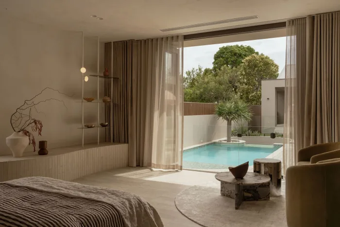A bedroom at ZOEI opening through sheer curtains to the pool.