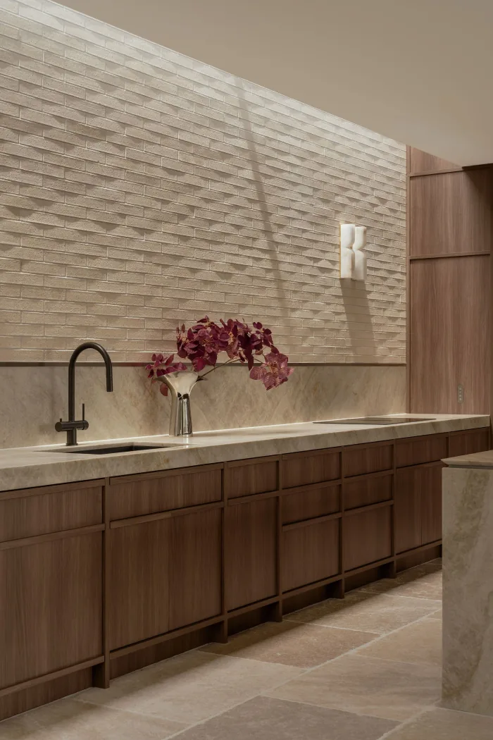 The textured stone splashback and brushed tapware in the ZOEI kitchen.