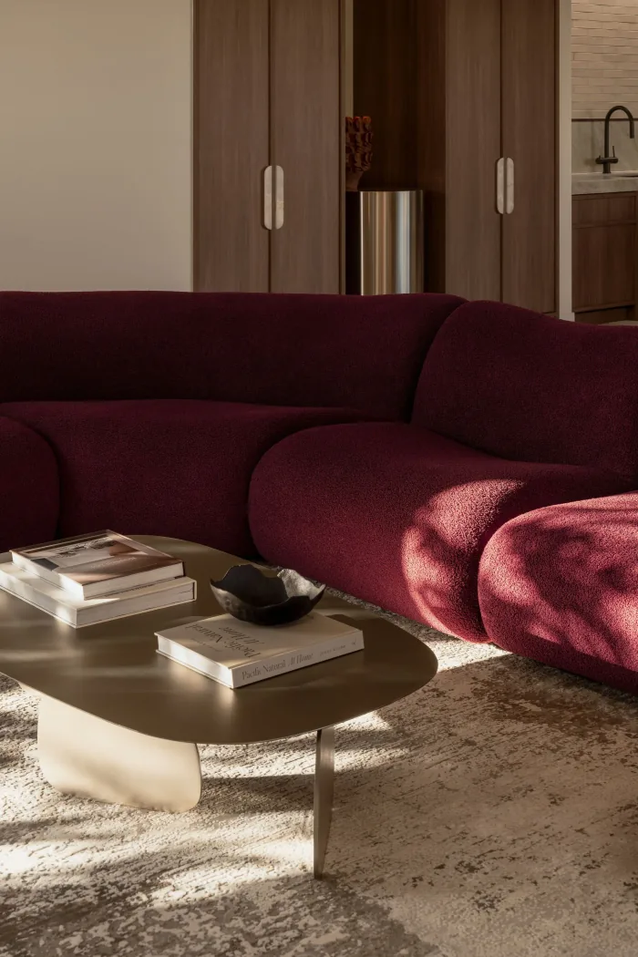 A curved coffee table and books styled on the wine bouclé sofa at ZOEI.