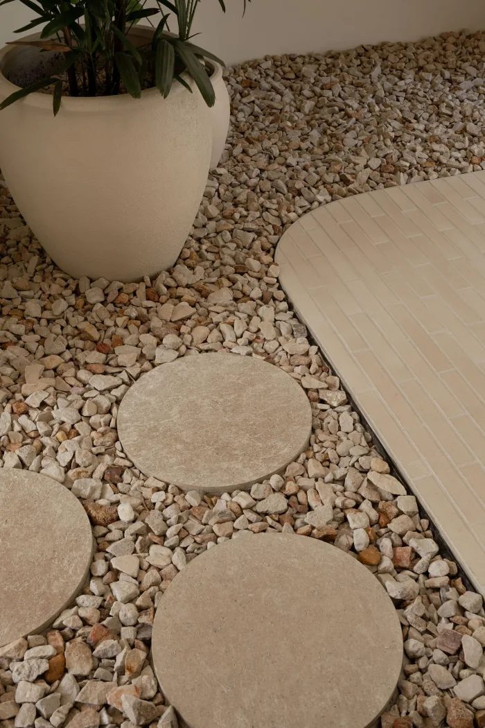 Round stone stepping pads set into river pebbles in a ZOEI courtyard.