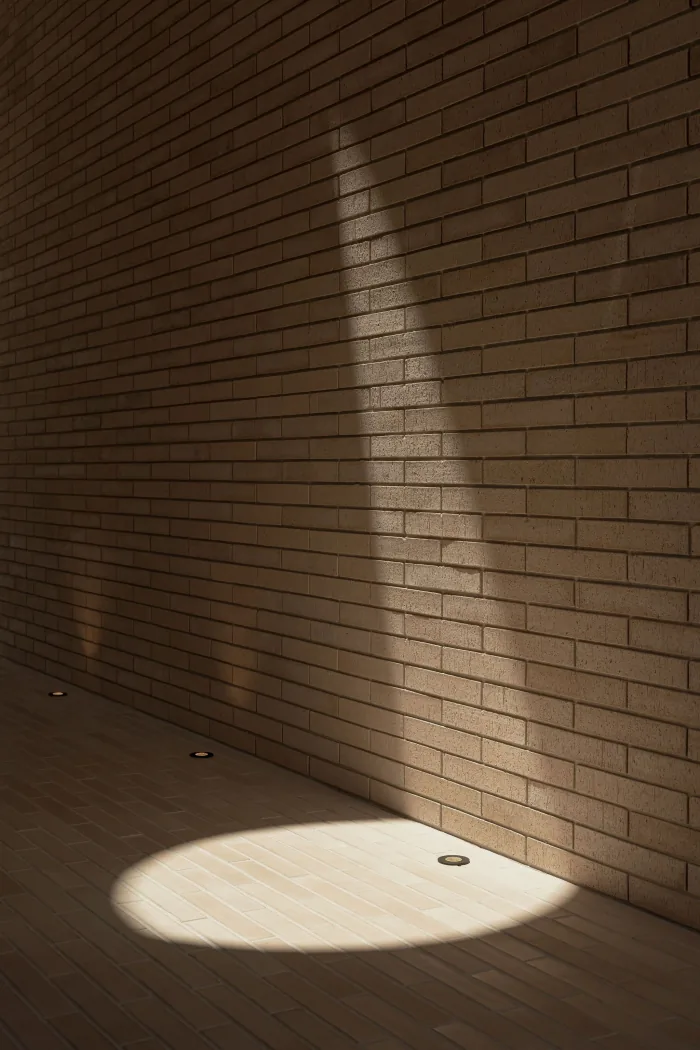 Raking light across a textured brick wall at ZOEI.